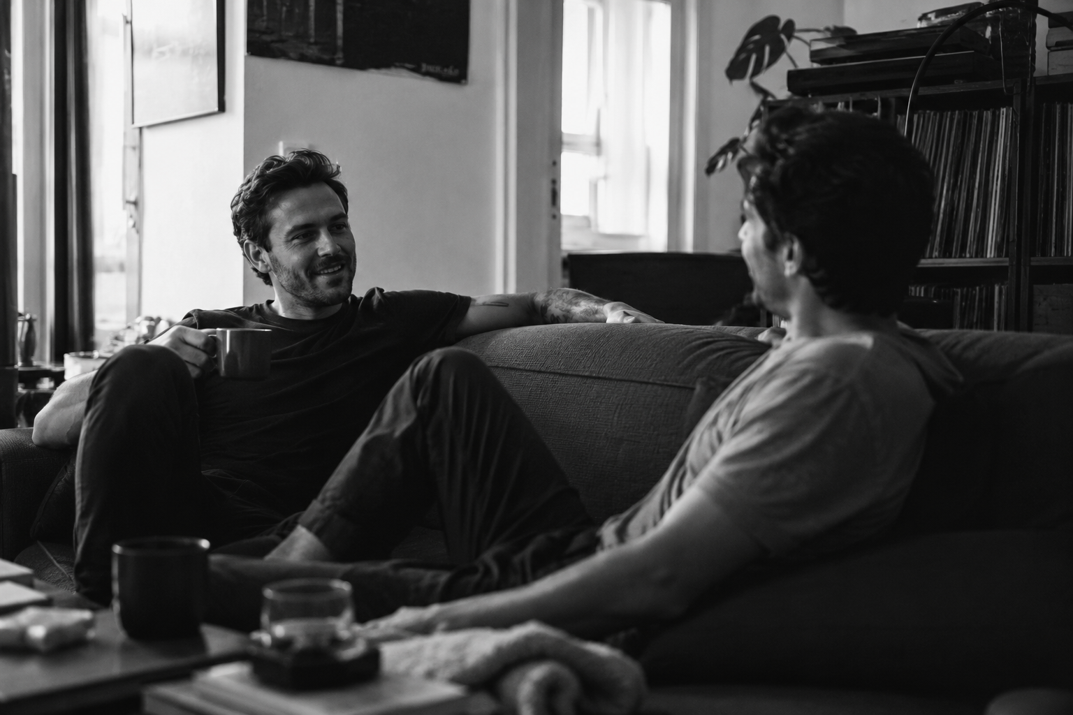 Two mates sitting on a sofa together with coffee